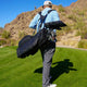 Man carrying a golf bag on a golf course with mountains in the background