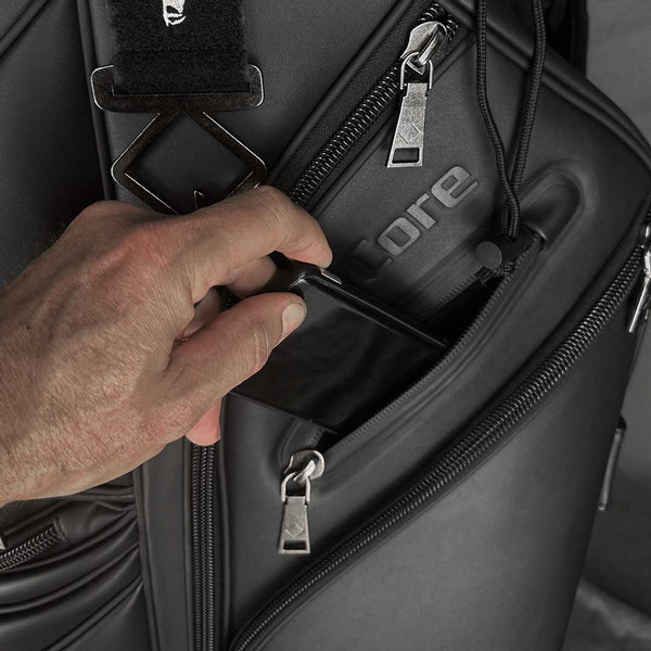 Person opening a black backpack with a visible brand logo.