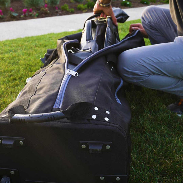 Person packing a golf travel bag on grass