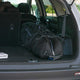 Black golf bag in the trunk of a car with a visible brand logo.