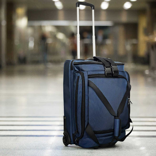 Blue suitcase with a black strap on a blurred indoor background
