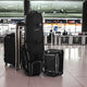 Black and gray suitcases with a visible brand logo in an airport setting